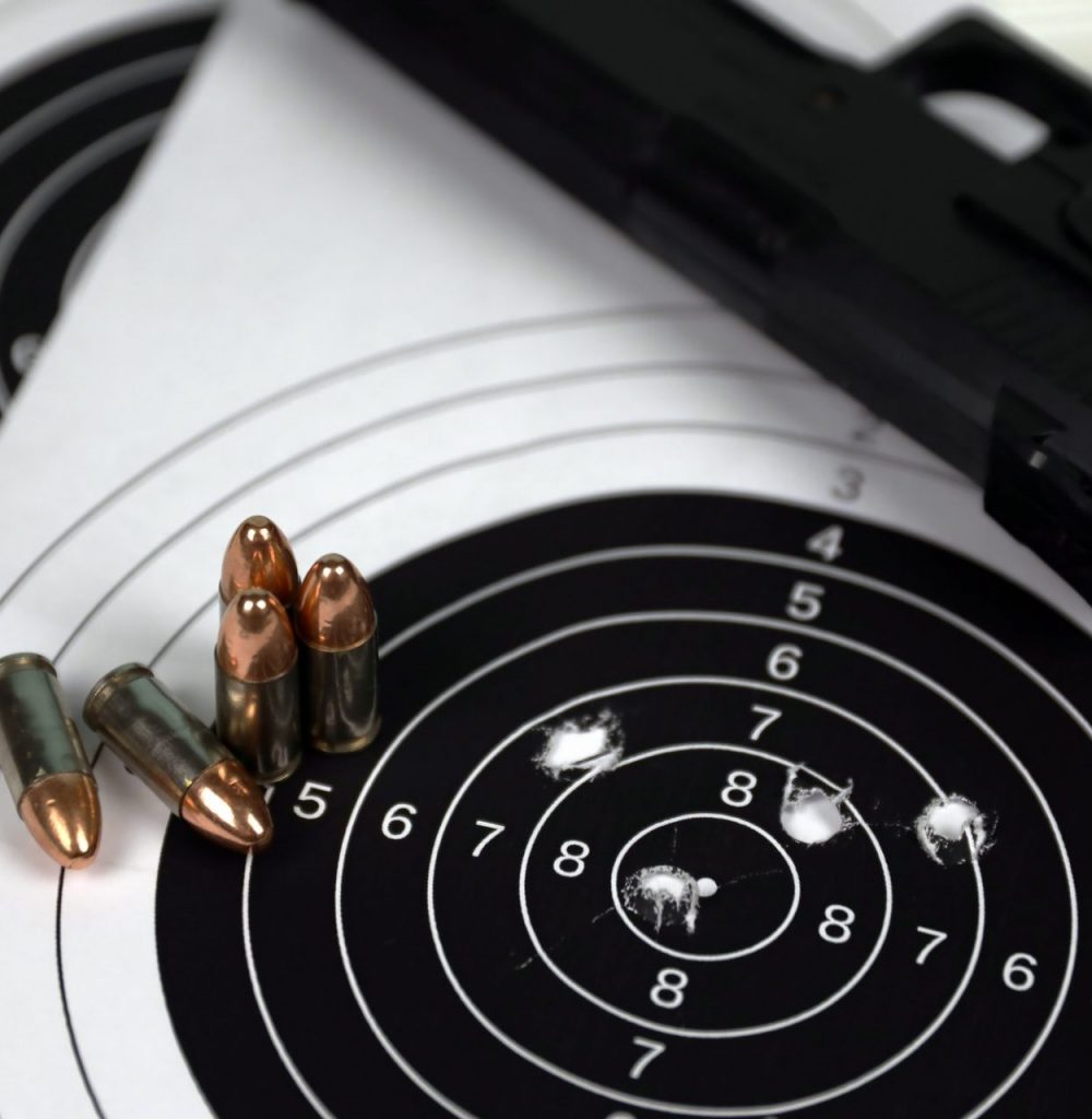 Gun and many bullets shooting targets on white table in shooting range polygon. Training for aiming